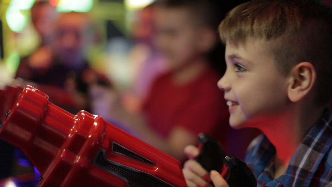 Young Boy Smiling Playing Arcade Game